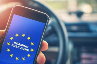 Людина користується смартфоном на тлі прапора Європейського Союзу