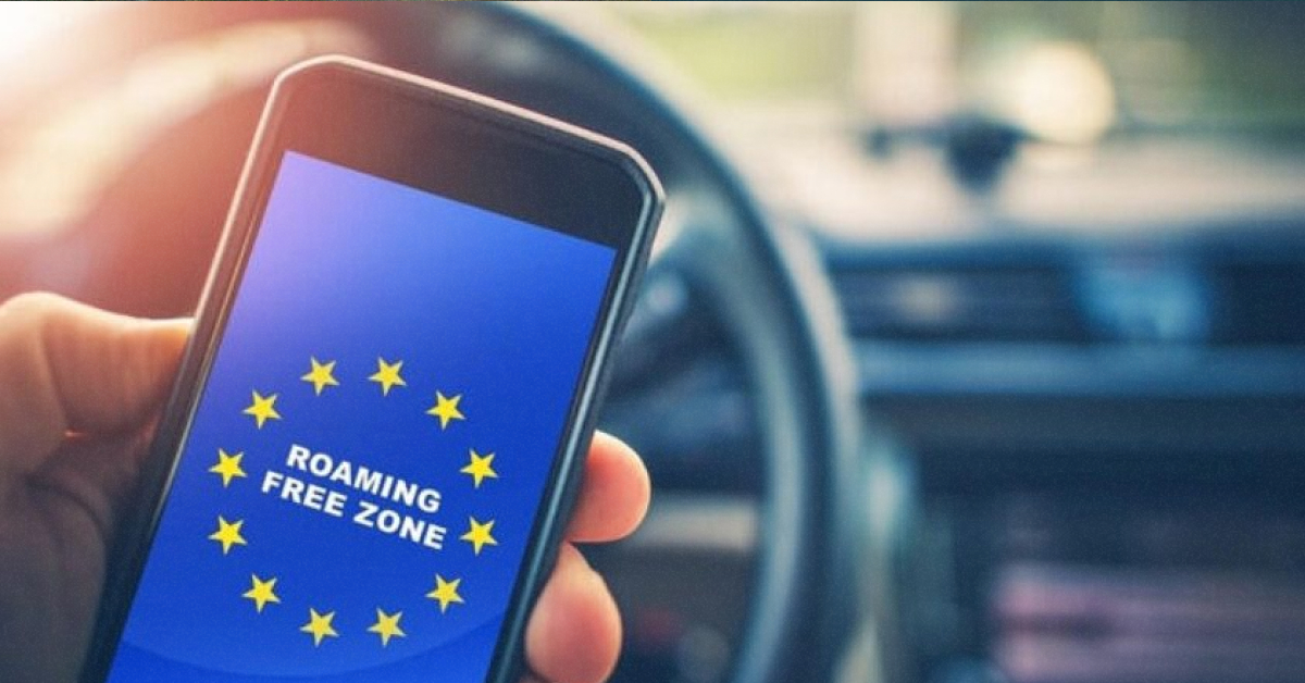 Людина користується смартфоном на тлі прапора Європейського Союзу