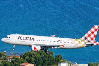 Літак авіакомпанії Volotea у фірмовій лівреї в небі на тлі моря