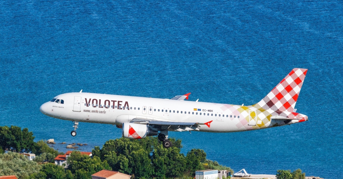 Літак авіакомпанії Volotea у фірмовій лівреї в небі на тлі моря