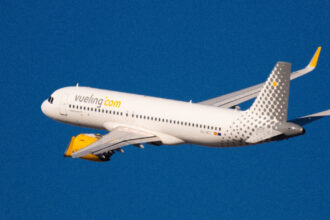 Літак Vueling у фірмовій лівреї на тлі блакитного неба