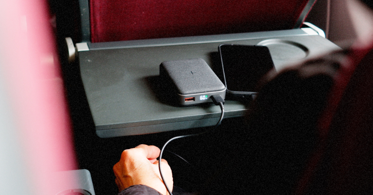 Пауербанк у руці пасажира на фоні ілюмінатора літака