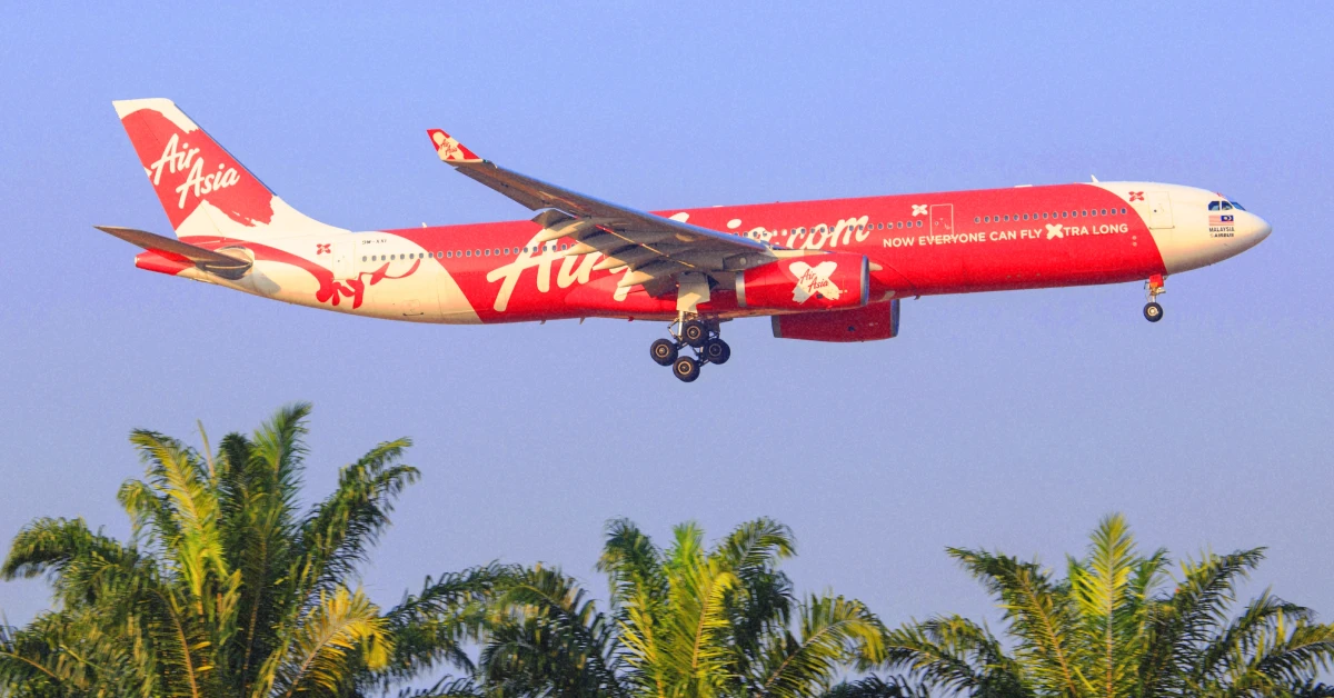 Яскраво-червоний літак AirAsia на тлі тропічного неба