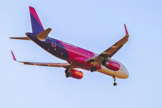 Рожевий літак Wizz Air на злітній смузі під час весняного заходу сонця