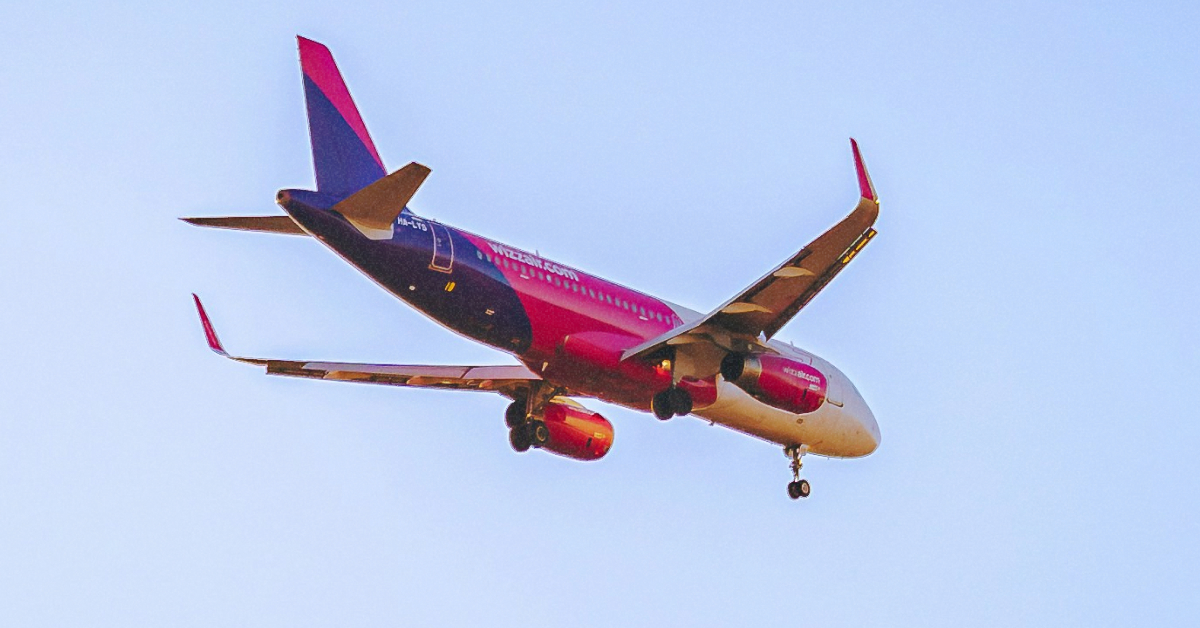 Рожевий літак Wizz Air на злітній смузі під час весняного заходу сонця