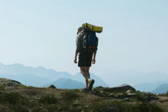 Група туристів із рюкзаками піднімається на гірський хребет під час заходу сонця