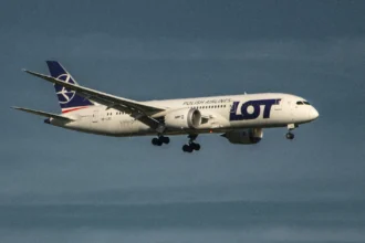 Літак авіакомпанії LOT Polish Airlines в полоті на тлі весняного неба