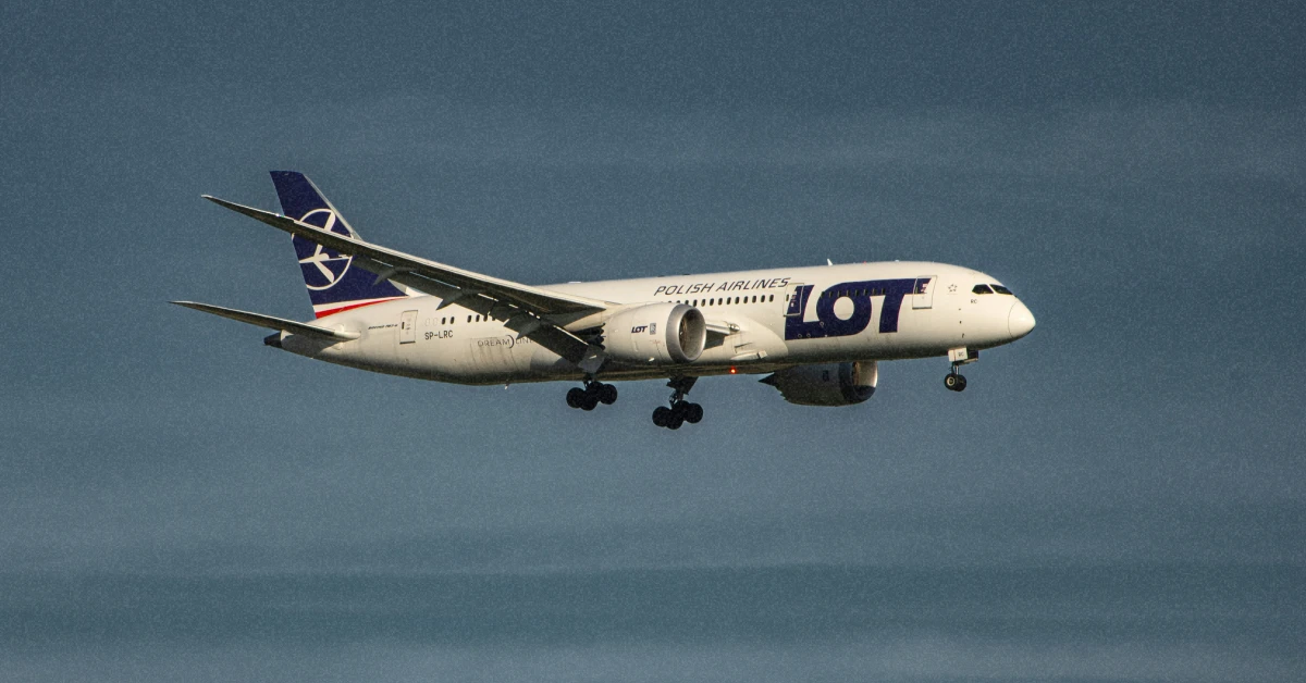 Літак авіакомпанії LOT Polish Airlines в полоті на тлі весняного неба
