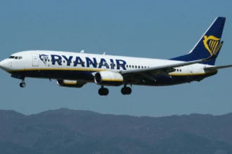 Літак Ryanair у небі на фоні яскравого весняного сонця
