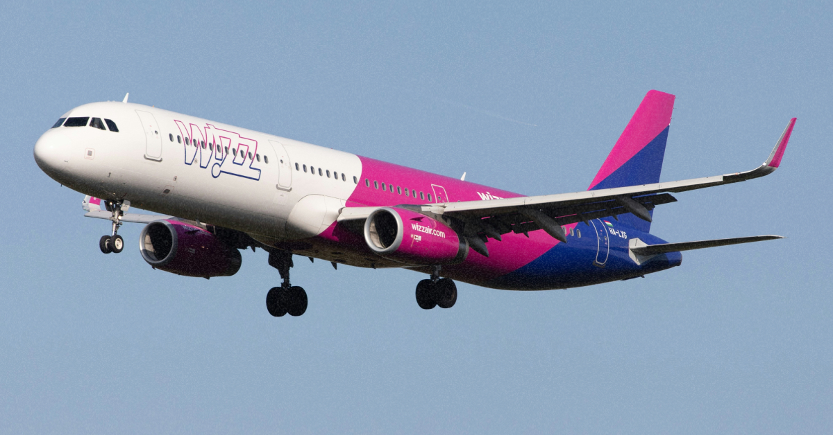 Літак Wizz Air у фірмових кольорах під час зльоту на фоні весняного неба