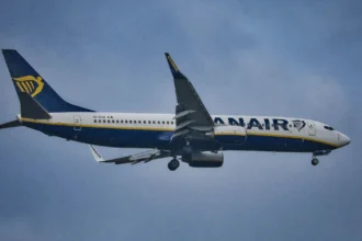 Літак Ryanair у небі на тлі яскравого літнього сонця