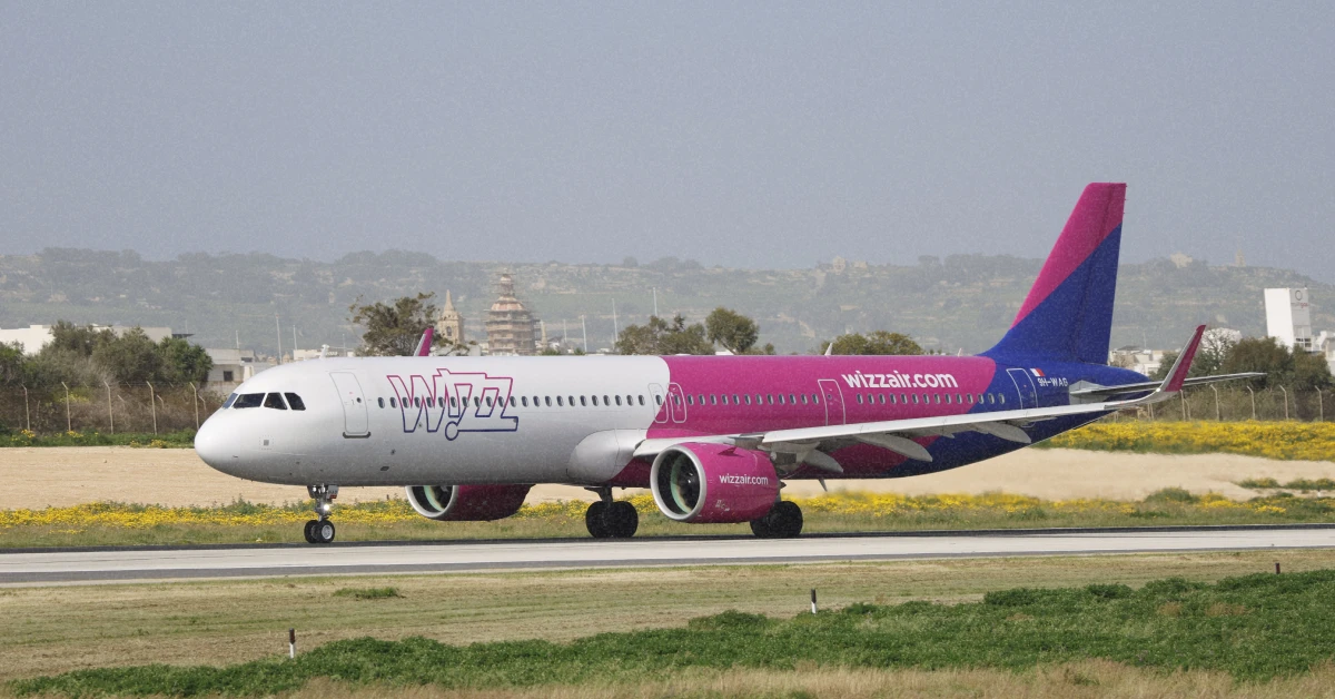 Яскраво-рожевий пасажирський літак Wizz Air здійснює посадку в європейському аеропорту