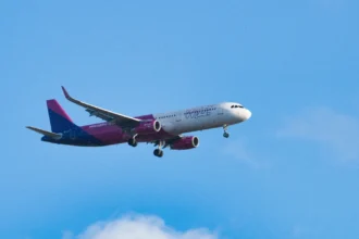 Пасажирський літак Wizz Air у фірмових рожевих кольорах злітає на тлі осіннього неба