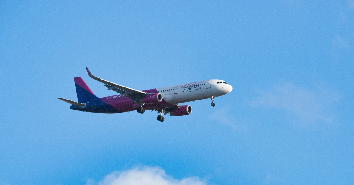 Пасажирський літак Wizz Air у фірмових рожевих кольорах злітає на тлі осіннього неба