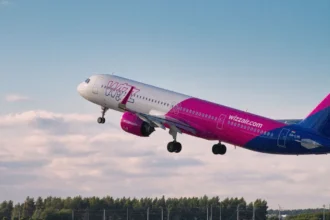 Яскравий рожево-білий літак Wizz Air піднімається в небо у сонячний літній день