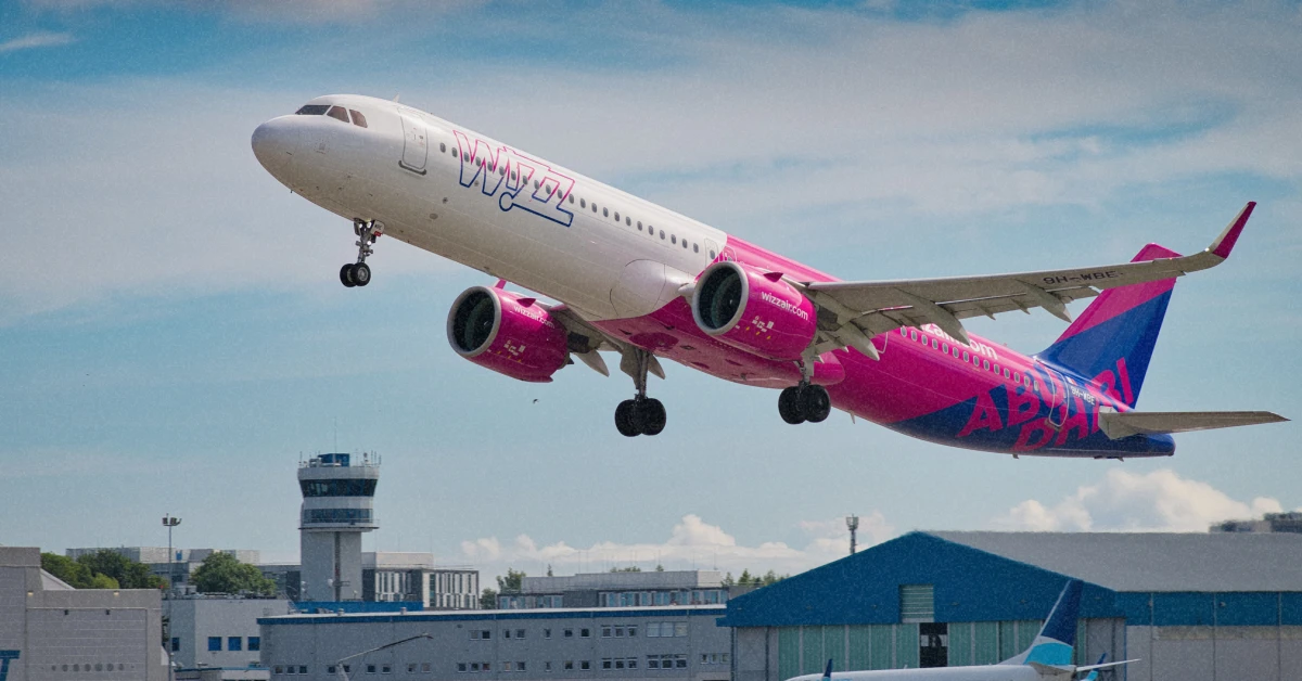 Фірмовий рожево-білий літак Wizz Air на злітній смузі у сонячний день