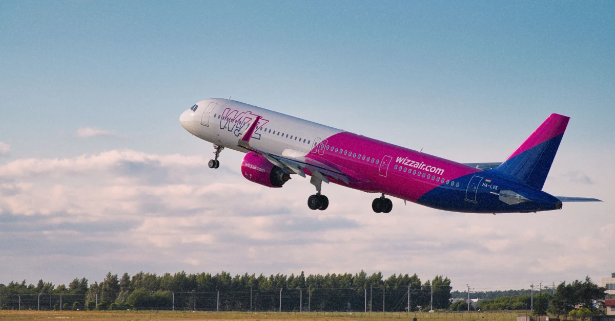 "Фірмовий рожево-білий літак Wizz Air на злітній смузі у сонячний день