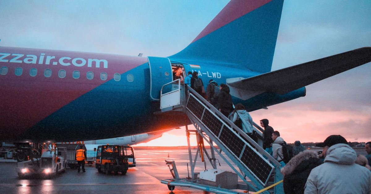 Пасажири піднімаються на борт літака Wizz Air у променях ранкового сонця